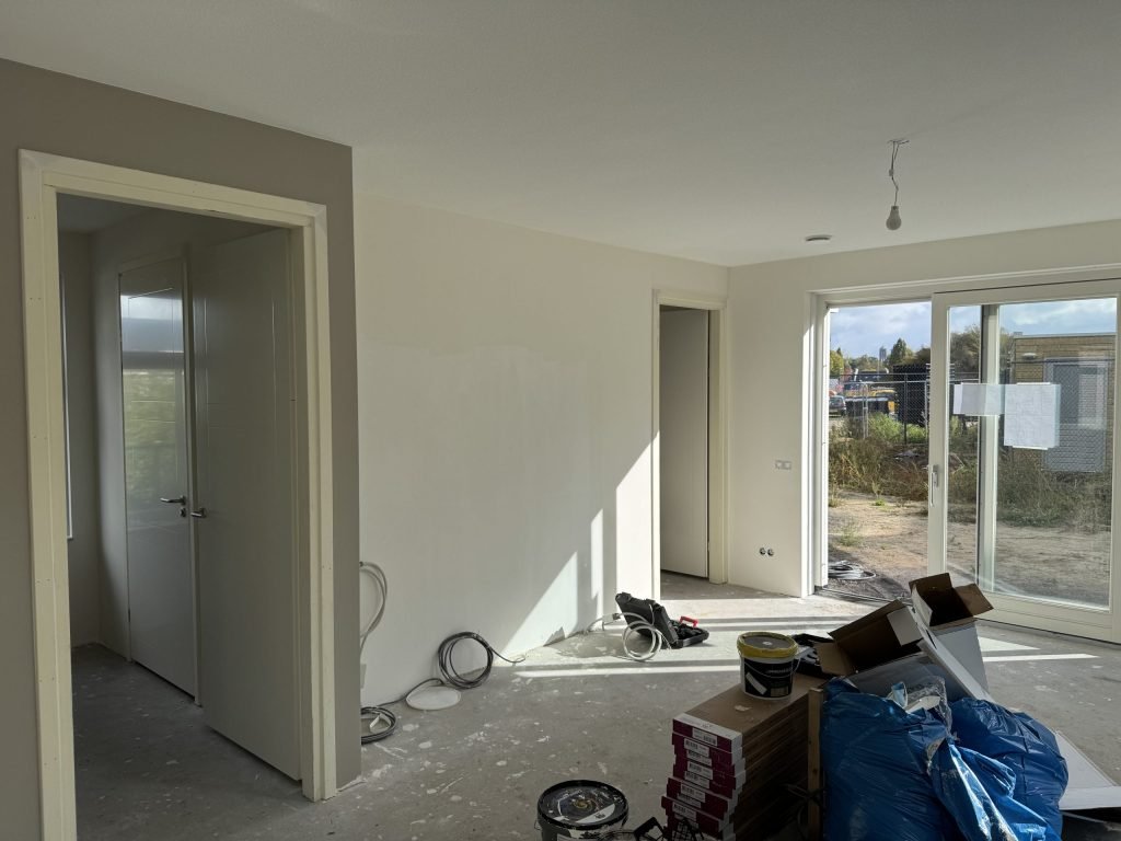 Nieuwbouwwoning tijdens de afwerking, met verfemmers en materiaal op de vloer