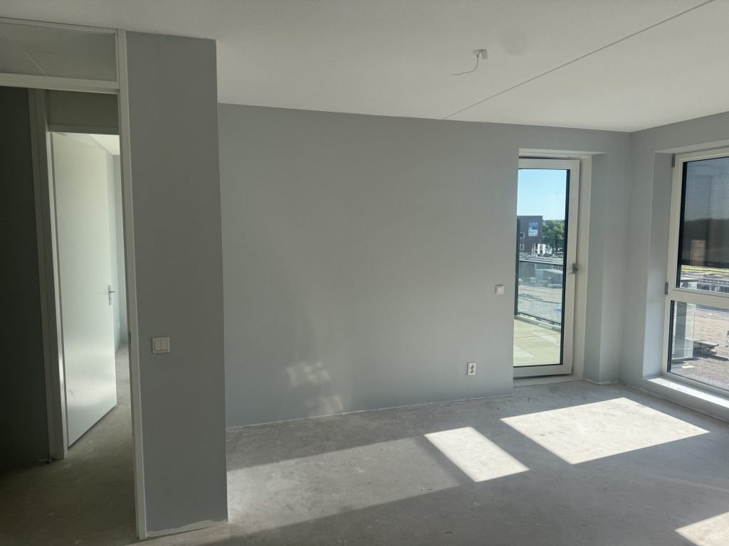 Woonkamer in een nieuwbouwwoning met egaal afgewerkte wanden in een lichtgrijze tint